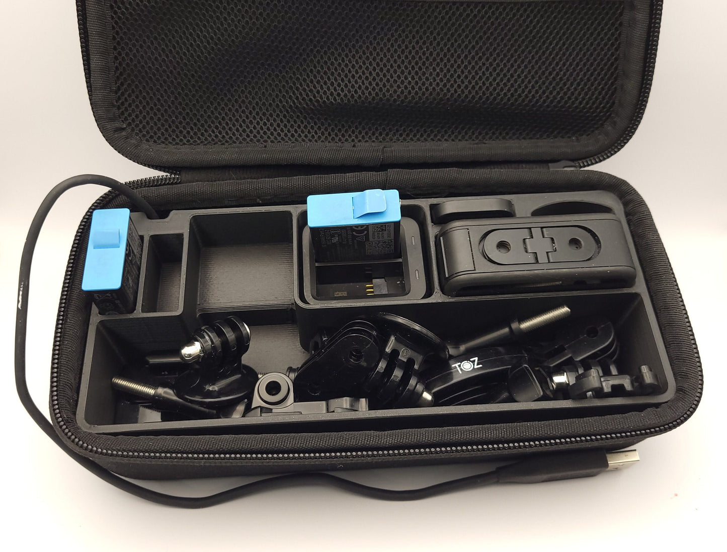 Black GoPro Case Organizer with Long Accessory Tray displayed in hard shell case with camera and accessories | Charge Batteries on the Go | Sturdy Protection | AirTag Slot | PLA or Heat Resistant PETG