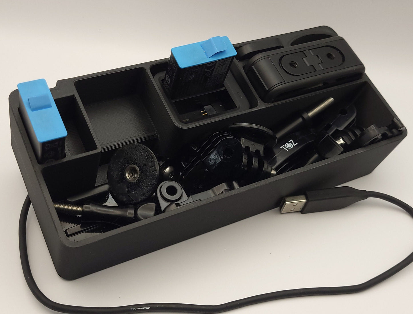 Black GoPro Case Organizer with Long Accessory Tray displayed with camera and accessories | Charge Batteries on the Go | Sturdy Protection | AirTag Slot | PLA or Heat Resistant PETG